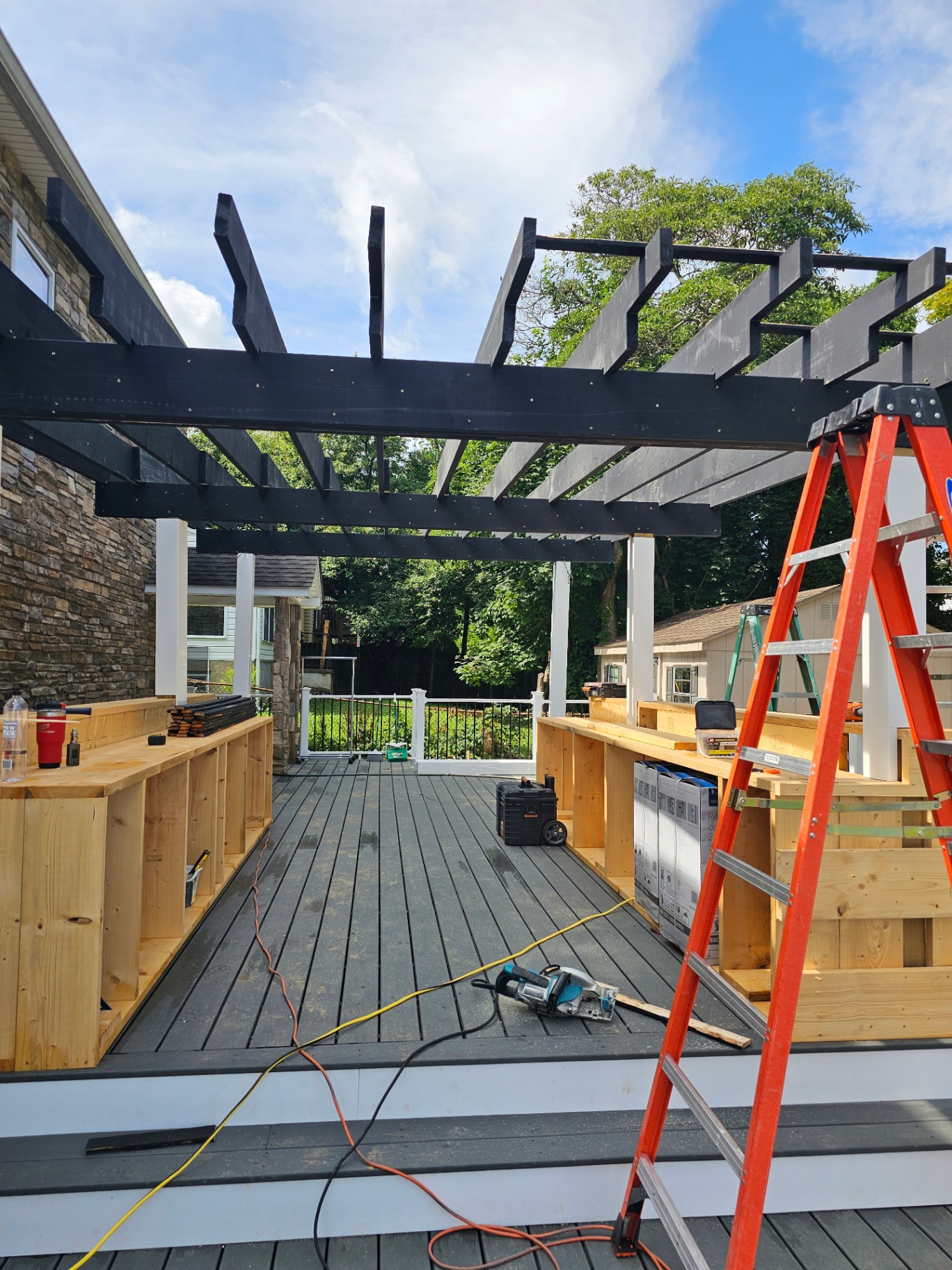 Black pergola framing over composite deck
